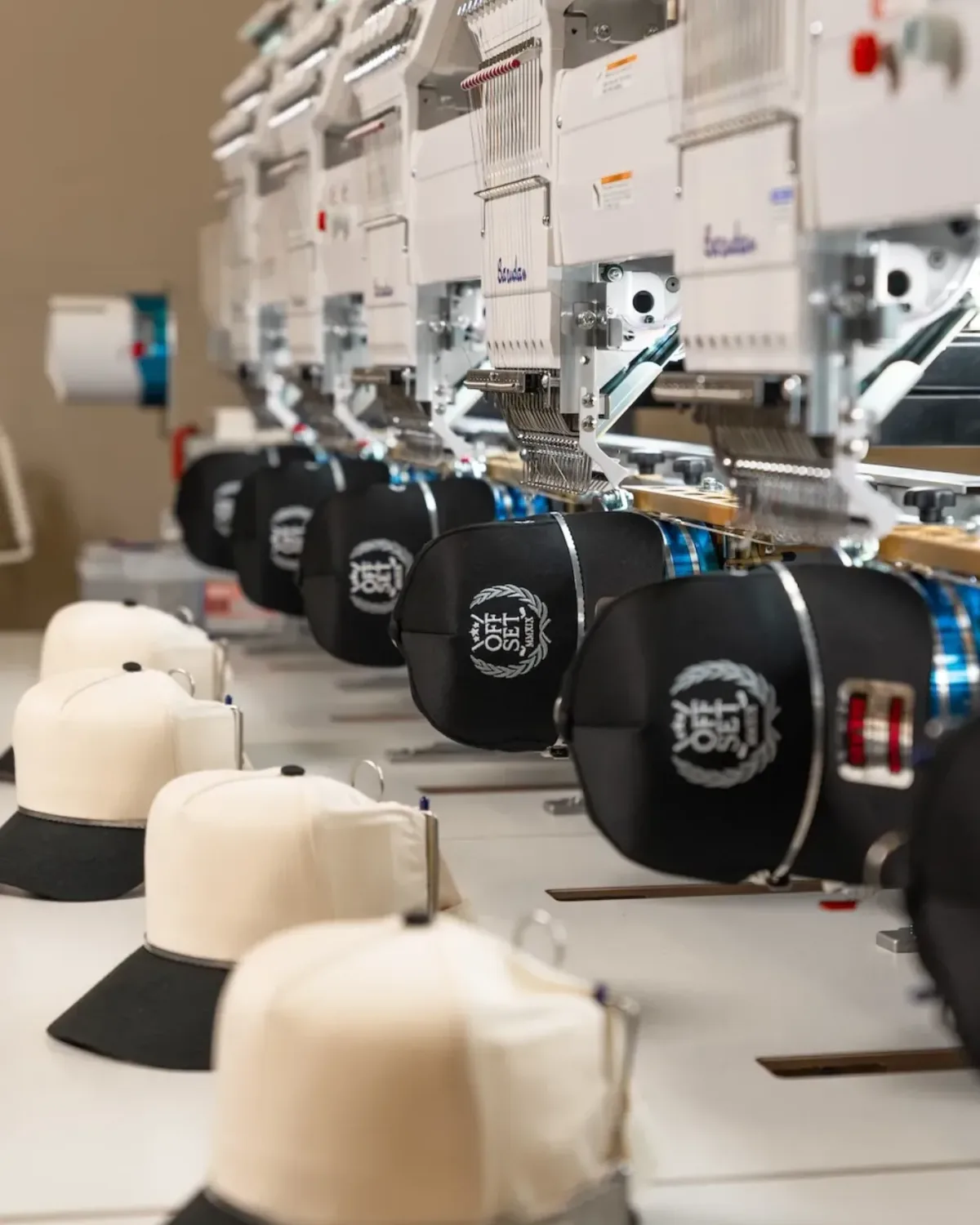 Row of commercial multi-head embroidery machines running a cap order at Elite Custom Apparel