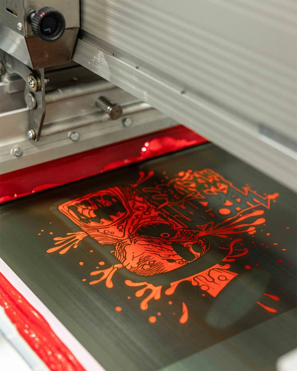 Squeegee and flooded screen mid-print on the automatic press at Elite Custom Apparel